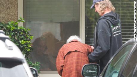 A touching photo shows an elderly woman talking through a window to her quarantined husband